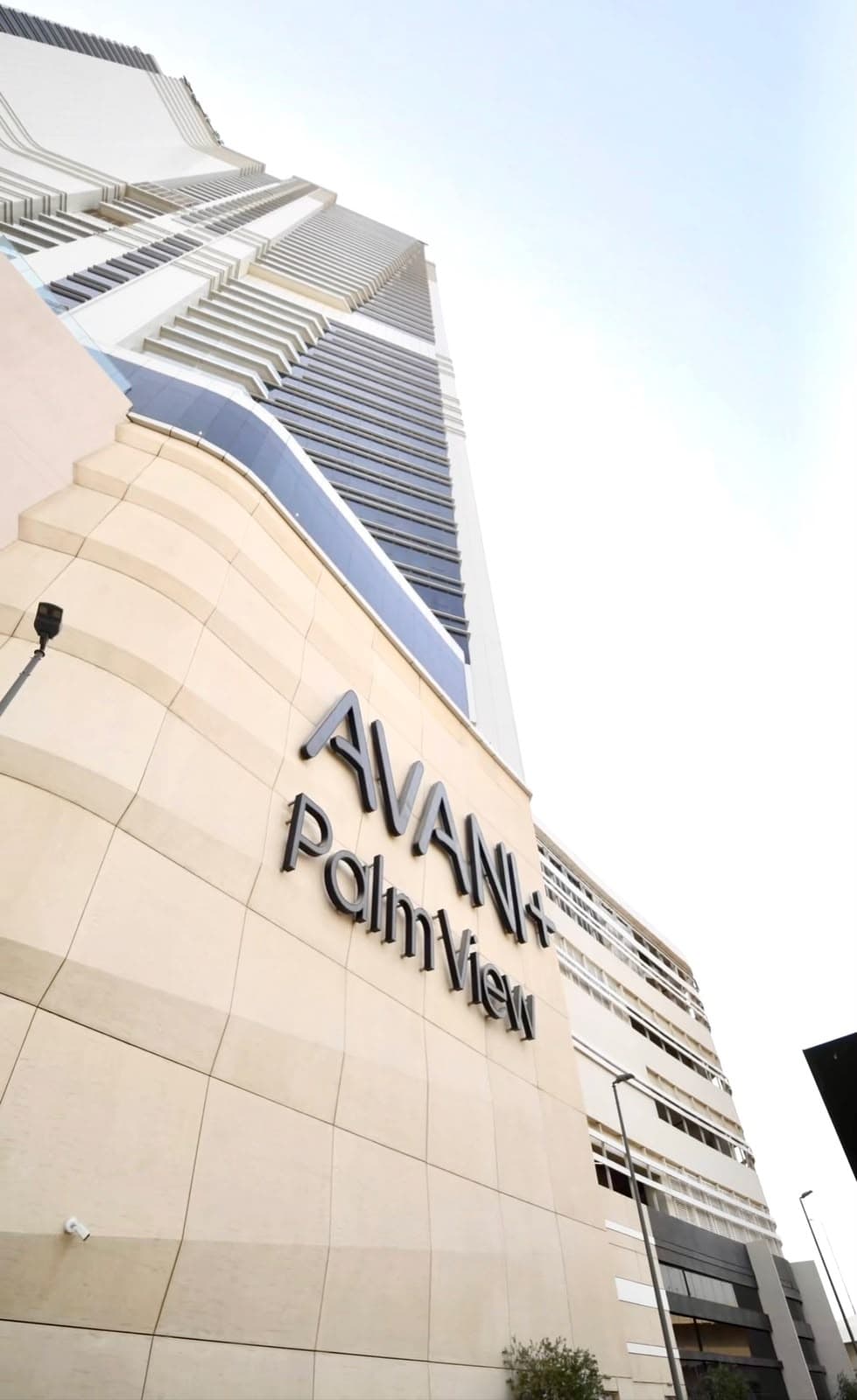 The Avani + Palm View tower seen from street level, its name mounted on the curved stone podium
