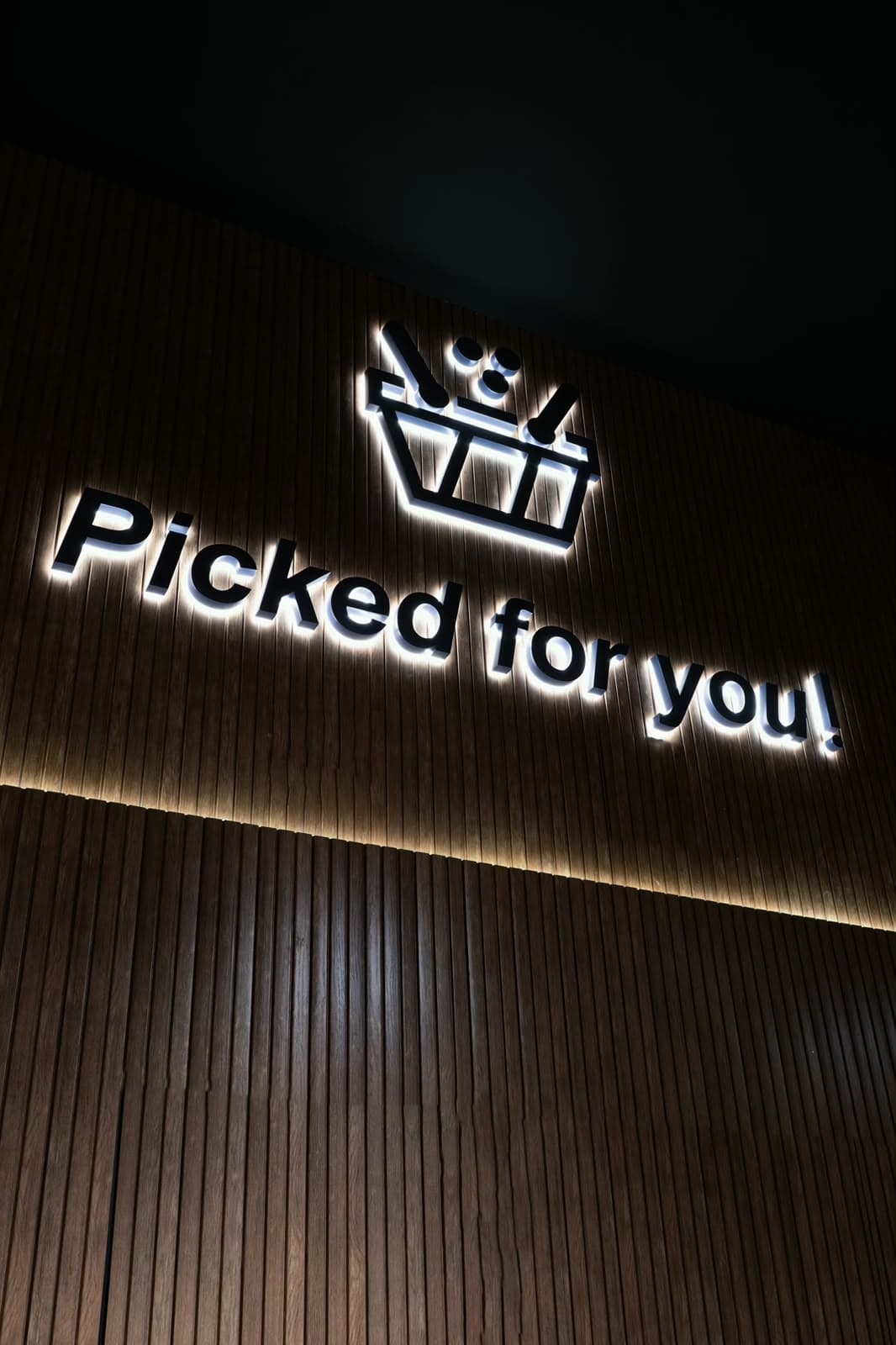 The illuminated Sella mark and the words Picked for you on a wall of vertical timber slats